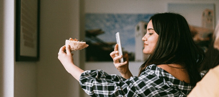 girl taking photo of pizza on smartphone
