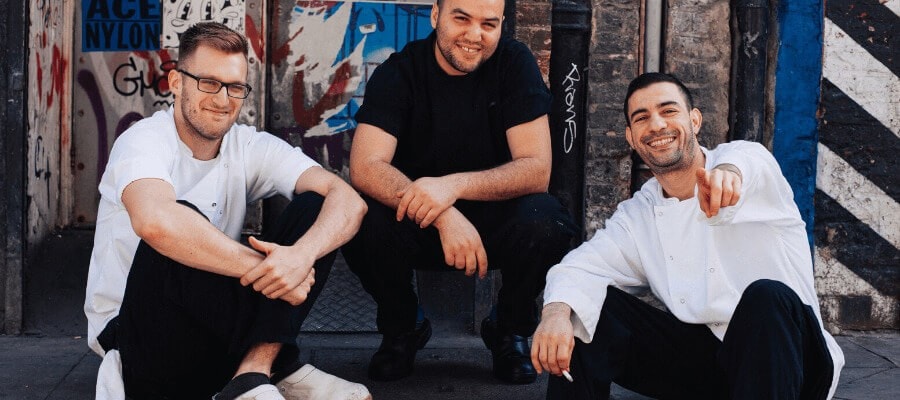 chefs sitting outside restaurant on steps